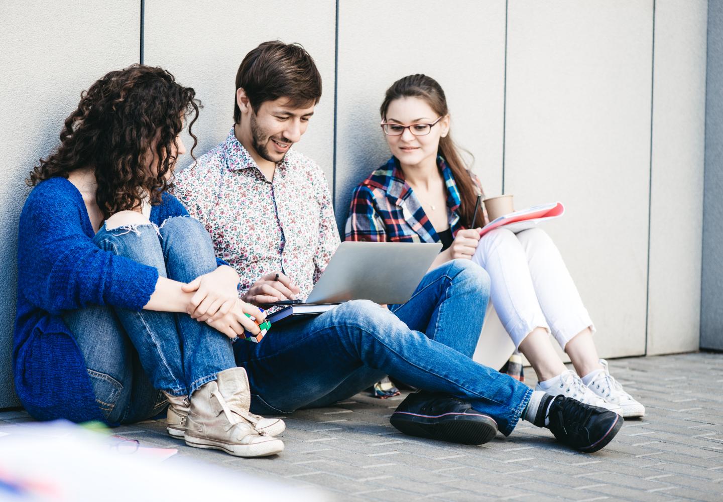 Young people are using different gadgets and smiling, sittin
